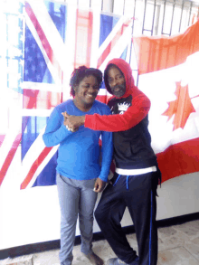 a man in a red hoodie is hugging a woman in front of a flag