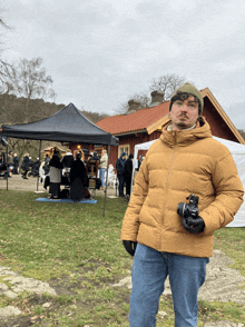 a man holding a camera in front of a red house