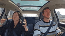 a man and a woman are sitting in a car and the man is wearing a sweater with a heart on the front