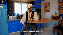 a man in a cowboy hat sits on a chair in front of a kitchen counter that says cuisine on it