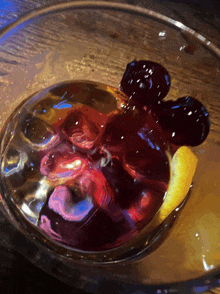 a glass filled with a purple liquid and a mickey mouse shaped ice cube