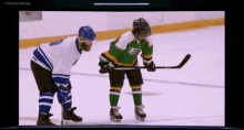 two hockey players are standing on the ice and one has the letter e on his shirt