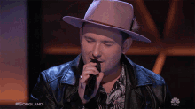 a man singing into a microphone with #songland on the bottom