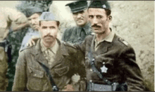 a group of men in military uniforms are standing next to each other in a field .