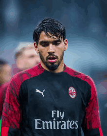 a man wearing a black and red fly emirates jersey