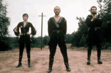 a man and two women standing in a field with a cross in the background