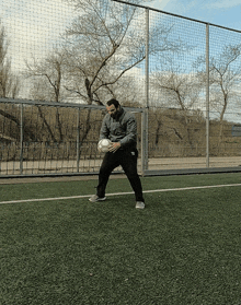 a man is holding a soccer ball on a soccer field