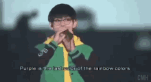 a man in a green jacket is singing into a microphone while wearing glasses .