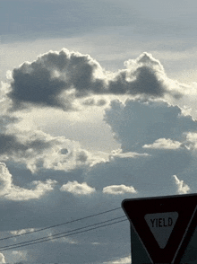 a yield sign with a cloud in the background