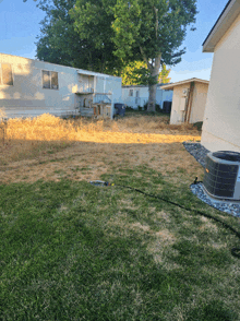 a backyard with a mobile home in the background and an air conditioner