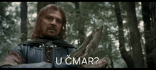 a man with a beard is holding a piece of wood with the words u cmar written on it
