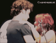 a man and woman are kissing in front of a microphone and the words carmenrsblue are on the bottom