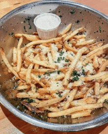 a bowl of french fries with a small cup of dipping sauce