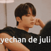 a young man is sitting on a couch with his hand on his chin and the words yechan de juli written above him