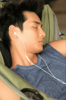 a man wearing earbuds is sleeping in a chair