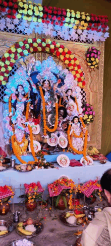 a statue of a woman is surrounded by flowers and offerings on a table