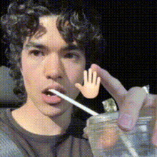 a man with curly hair is drinking from a plastic cup
