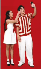 a man in a red and white shirt takes a selfie with a woman