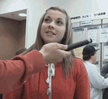 a woman in a red shirt is being interviewed by a man with a microphone in front of a sports news board