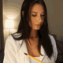 a woman in a white shirt holds a pencil in her hand