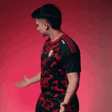 a man in a red and black shirt with the word adidas on it