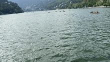 a group of people are in a boat on a lake with mountains in the background