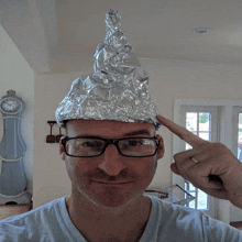 a man wearing glasses and an aluminum foil cone on his head