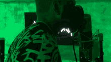 a man is singing into a microphone in front of a green wall