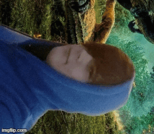 a person wearing a blue hoodie is laying down in a forest