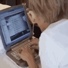 a person is typing on a laptop computer while wearing glasses .