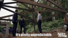 a group of men standing in front of a wooden structure with the words " it 's pretty unpredictable " below them