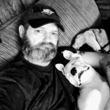 a man with a beard is sitting on a couch holding a stuffed animal dog .