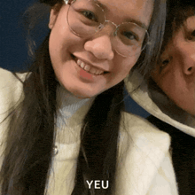 a woman wearing glasses is smiling next to a man and the word yeu is on the bottom