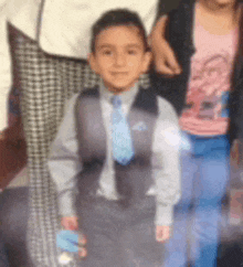 a young boy in a suit and tie is standing next to a girl