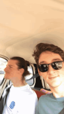 a man wearing sunglasses sits in the back seat of a car