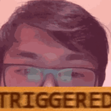 a close up of a man wearing glasses with the word triggered behind him .