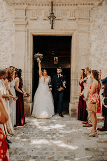 a bride and groom are walking out of a church surrounded by their wedding party