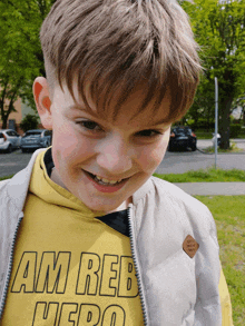 a young boy wearing a yellow shirt that says " am reb hero "