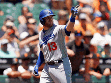 a baseball player wearing a dodgers jersey is pointing up