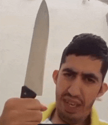 a man is holding a large knife in his hand and making a face .