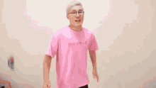 a man wearing glasses and a pink shirt is standing in front of chinese writing