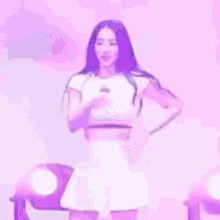 a woman is standing on a stage wearing a white skirt and a crop top with cherries on it .