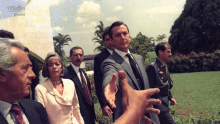 a man in a suit shakes hands with a woman in a pink dress