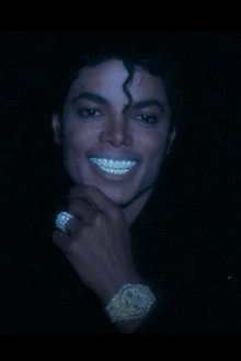 a man with braces on his teeth wears a watch and a ring