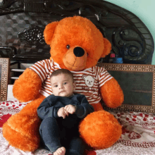 a baby is sitting next to a teddy bear wearing a shirt that says " it 's my teddy "