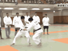 a group of men are watching a judo match with one man wearing a shirt that says ' x ' on it