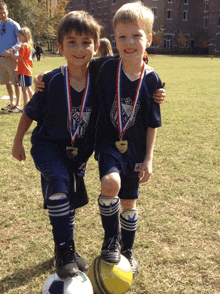 two young boys with medals on their shirts are posing for a picture