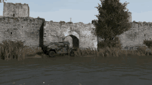 a military vehicle is parked in front of an old stone wall