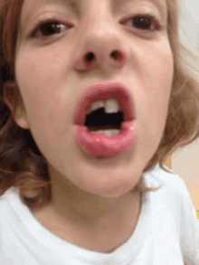 a close up of a child 's face with her mouth open and a black object in it