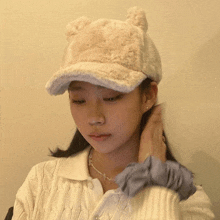 a young girl wearing a white hat with ears on it